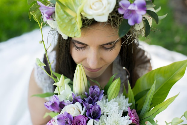 Bella giovane sposa in una corona con un bouquet in mano