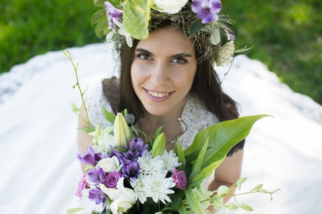 Bella giovane sposa in una corona con un mazzo di fiori in mano