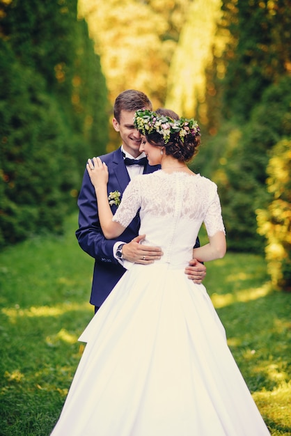 Bella giovane sposa sensuale e sposo bello che abbracciano tenero nel parco europeo al tramonto.