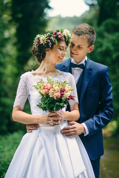 Bella giovane sposa sensuale e sposo bello che abbracciano tenero nel primo piano del parco