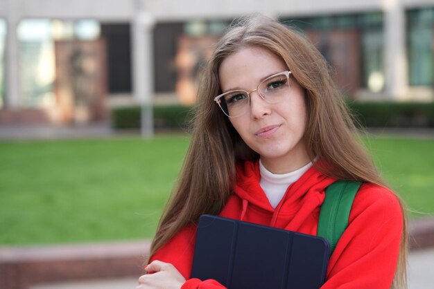 Bella giovane studentessa universitaria o universitaria ragazza felice all'aperto nel campus con gli occhiali con apparecchi dentali