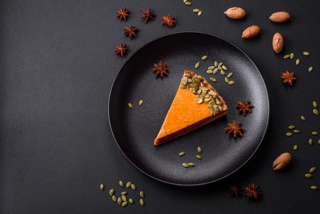 Bella gustosa torta di zucca con fette su un piatto di ceramica nera su uno sfondo di cemento scuro