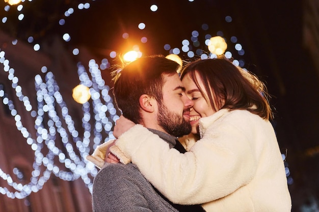 Bella illuminazione a ghirlanda Felice giovane coppia festeggia il nuovo anno all'aperto sulla strada