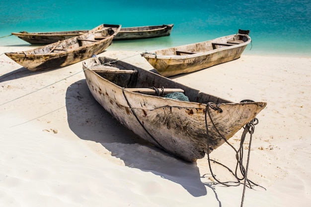 Bella linea costiera di Zanzibar. Barche di pescatori in legno sulla spiaggia sabbiosa con sfondo blu acqua, Zan