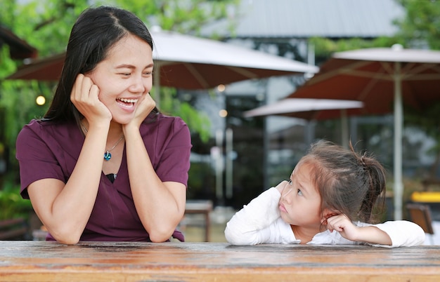 Bella madre asiatica felice che parla con sua figlia sulla tavola di legno al restau all&#39;aperto