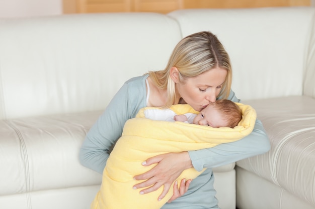 Bella madre bacia il suo bambino che è avvolto in una copertina