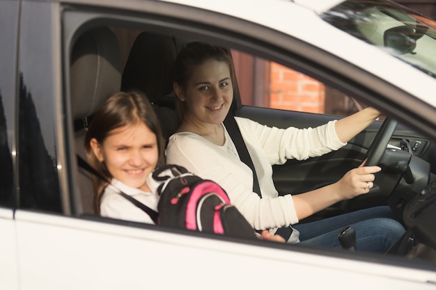 Bella madre che guida l'auto con la figlia a scuola