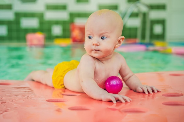 Bella madre che insegna alla bambina carina come nuotare in una piscina Bambino che si diverte in acqua con la mamma