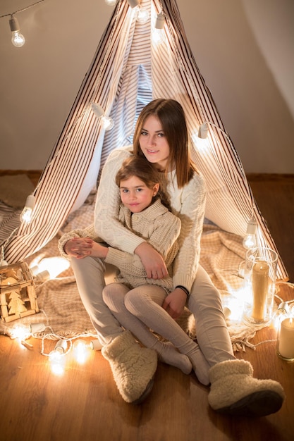 Bella madre e figlia vigilia di Natale seduti nell'accogliente interno Anno nuovo