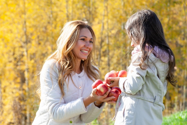 Bella madre, figlia gioca con mele rosse