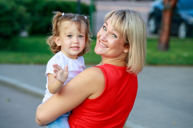 Bella mamma bionda in una maglietta rossa con sua figlia. ritratto di gruppo