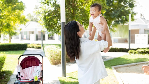 Bella mamma che tiene in braccio una bambina all'aperto sotto il sole dayx9