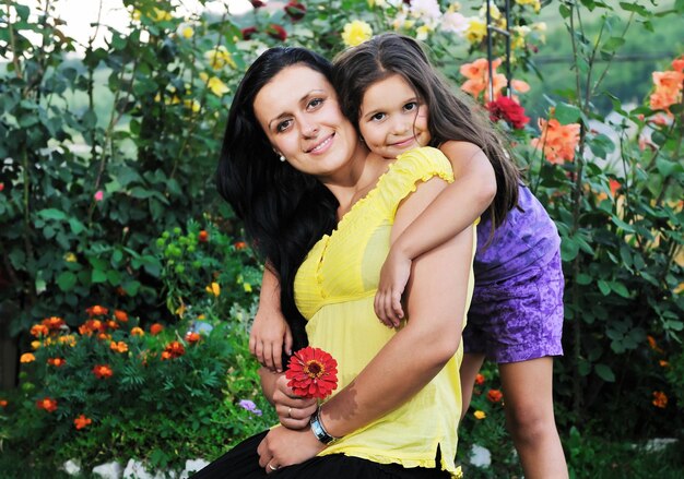 bella mamma e figlia all'aperto in giardino insieme al fiore si divertono e si abbracciano