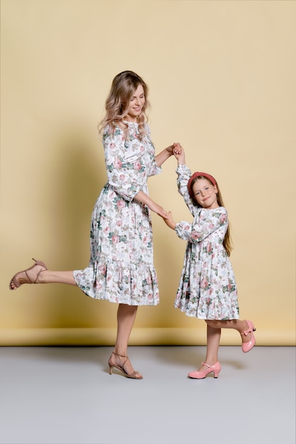 Bella mamma e figlia in abiti identici che ballano in studio