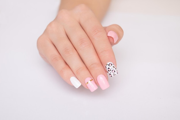 Bella mano femminile con manicure rosa unghie design stampa leopardo su sfondo bianco