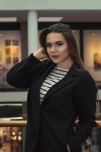 Bella modella bruna in cappotto caldo nel centro commerciale