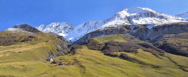 Bella montagna alpina europea con sfondo picco nevoso sotto il cielo blu