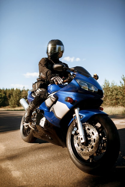 Bella moto su una strada forestale. Divertiti a guidare una strada deserta durante un giro in moto sotto i caldi raggi del sole del tramonto.