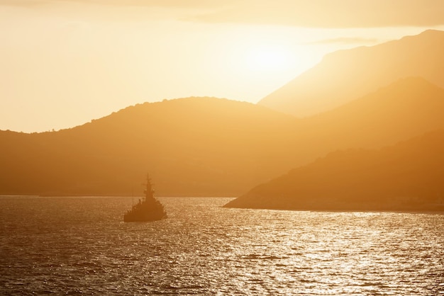 Bella nave marina che galleggia sull'acqua e sulla costa rocciosa all'alba o al tramonto Tonica