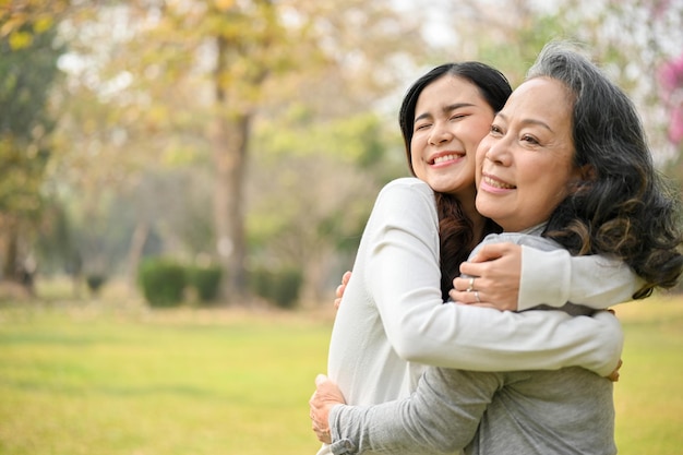 Bella nipotina asiatica che trascorre del tempo con sua nonna che le dà un grande abbraccio