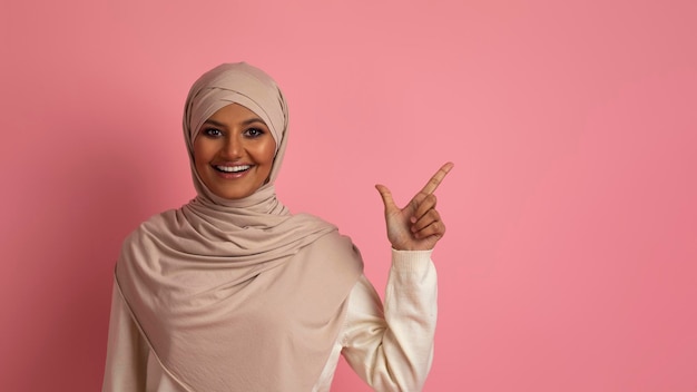 Bella offerta Donna islamica sorridente In Hijab che punta da parte allo spazio della copia