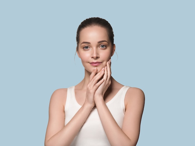 Bella pelle donna sana faccia mano toccando sfondo di colore della pelle fresca e pulita sana. Blu