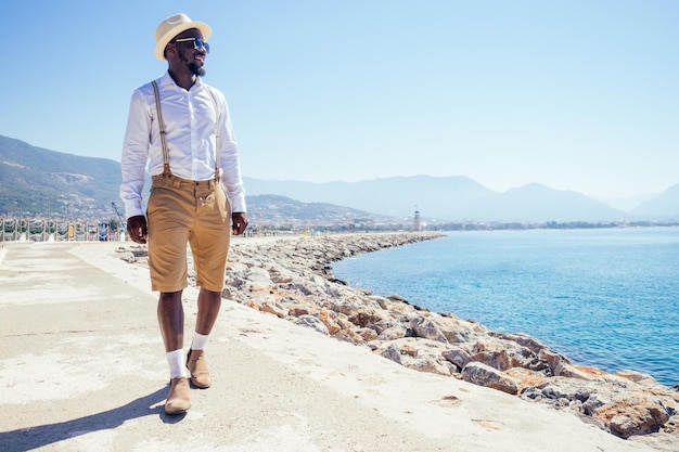 Bella persona afroamericana look casual alla moda vestito in camicia bianca cappello di paglia a piedi dalla costa di Tyrkey