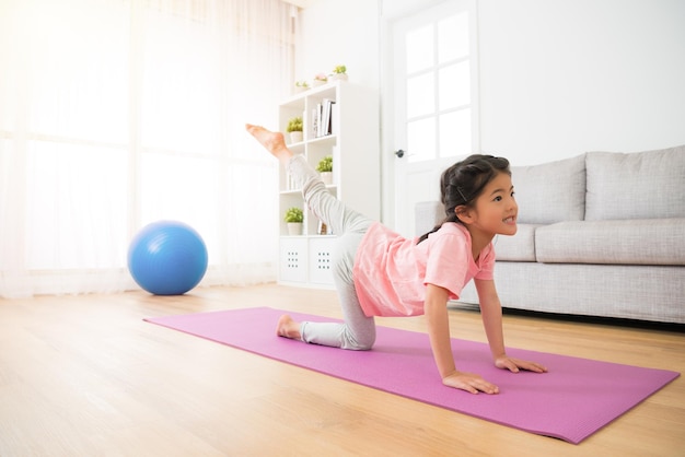 bella piccola ballerina asiatica che usa il tempo libero in vacanza a casa facendo esercizi di yoga per allenare la morbidezza del corpo e mantenere la salute personale facendo sport nella stanza.