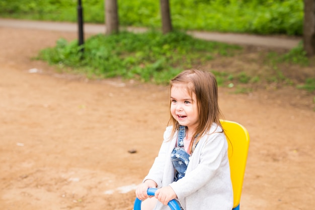 Bella piccola neonata sveglia sul parco giochi per bambini