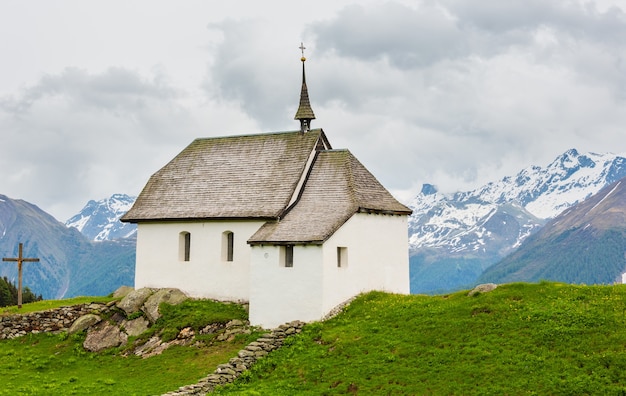 Bella piccola vecchia chiesa nel paesino di montagna delle Alpi di Bettmeralp, Svizzera. Vista nuvolosa di estate.