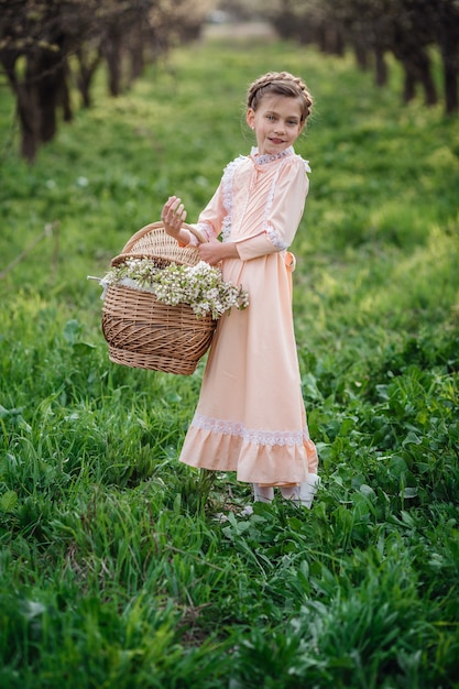 Bella ragazza 6-7 anni in posa in giardino. Tempo di Pasqua. gode della primavera e del caldo. Bellissimo giardino primaverile. Infanzia felice, pace e concetto di felicità. Fiore aromatico e vintage retrò.