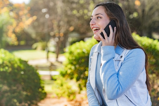 Bella ragazza adolescente che parla sul suo telefono cellulare in un parco