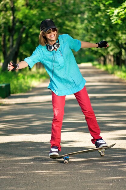 Bella ragazza adolescente con lo skateboard nel parco verde