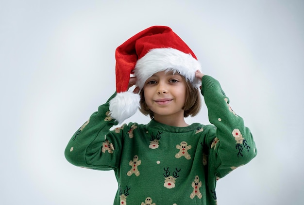 Bella ragazza adolescente in cappello di Babbo Natale seduto e sognando un regalo esprime felicità e anticipazione su sfondo bianco