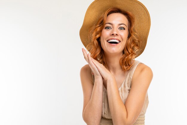 bella ragazza affascinante tenera in un abito e un cappello di paglia su un muro bianco