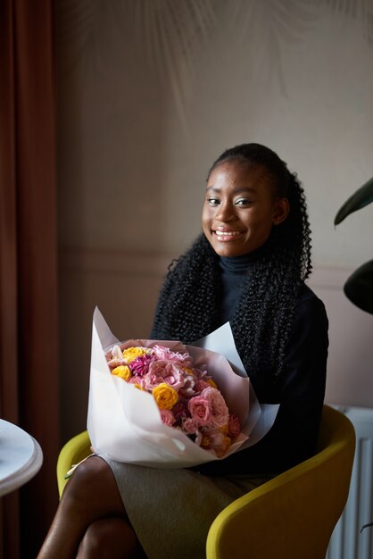 bella ragazza afroamericana che tiene un mazzo di fiori in un appuntamento in un caffè