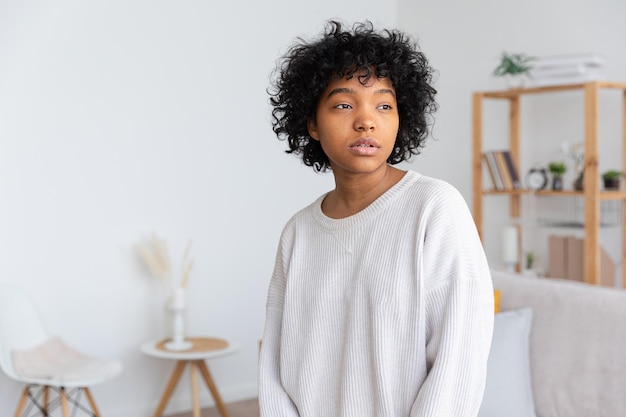 Bella ragazza afroamericana con acconciatura afro a casa al coperto Giovane donna africana con capelli ricci in soggiorno Concetto di vita domestica di persone etniche di bellezza