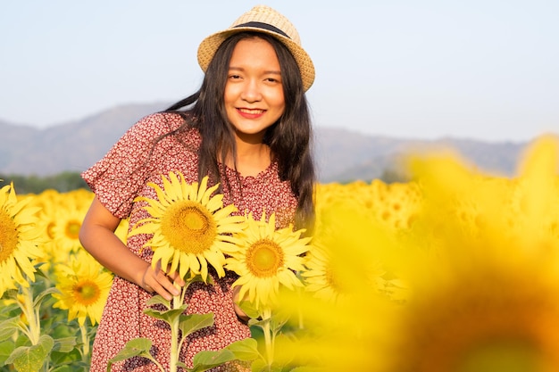 Bella ragazza al giacimento del girasole con cielo blu