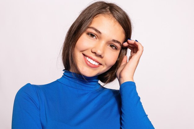 Bella ragazza alla moda hipster. Foto di giovane donna piacevole positiva in calzini alti al ginocchio blu con fondo bianco. guarda la telecamera. guardando la telecamera e sorridendo