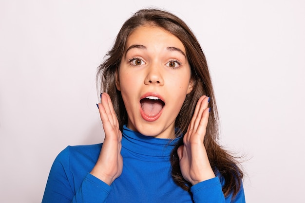 Bella ragazza alla moda hipster. Foto di giovane donna piacevole positiva in calzini alti al ginocchio blu con fondo bianco. guarda la telecamera. sorpreso