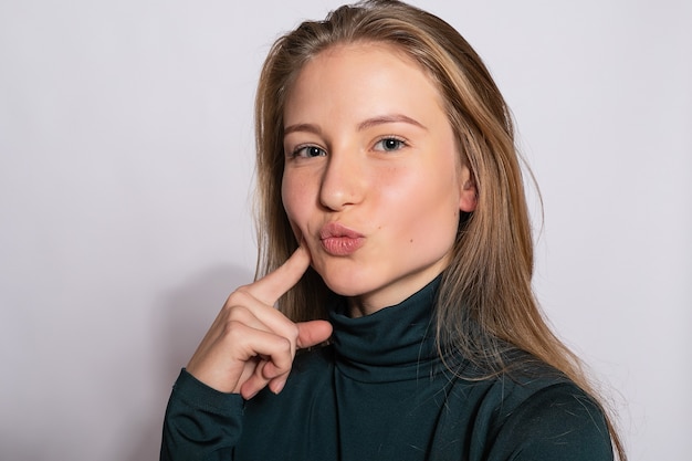 Bella ragazza alla moda hipster. Foto di giovane donna piacevole positiva in calzini alti al ginocchio verdi con sfondo bianco. guarda la telecamera.