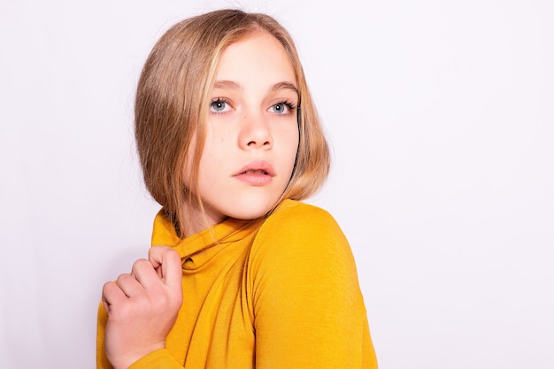 Bella ragazza alla moda hipster. Foto di giovane donna piacevole positiva in gambaletto giallo con sfondo bianco. guardando lontano