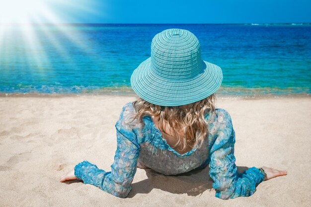 Bella ragazza alla moda in cappello sui precedenti della spiaggia