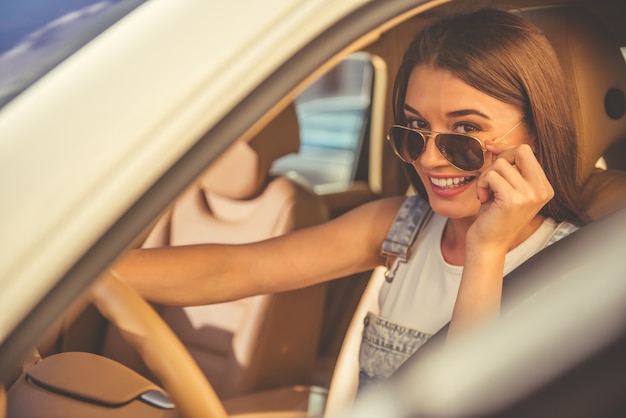 Bella ragazza alla moda in occhiali da sole alla guida di un'auto