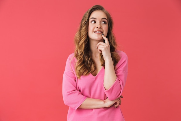 Bella ragazza allegra che indossa abiti casual in piedi isolata sul muro rosa, guardando lontano