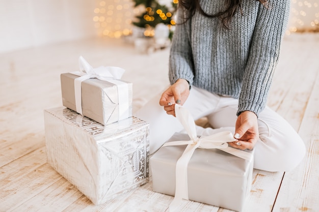 Bella ragazza allegra felice con i regali di Natale sullo sfondo di un albero di Capodanno a casa