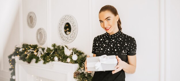 Bella ragazza allegra felice con i regali di Natale sullo sfondo di un albero di Capodanno a casa