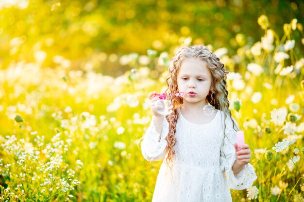 Bella ragazza allegra in un cappello di paglia in un campo giallo con i fiori