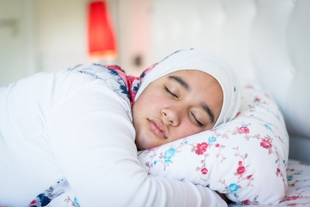 Bella ragazza araba sul letto nella camera da letto moderna