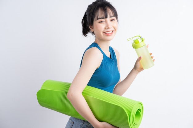 Bella ragazza asiatica che indossa il vestito di yoga su bianco